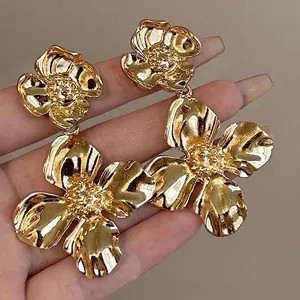 Macro close-up view of luxury gold floral drop earrings with intricate textured petals.