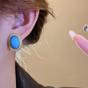 Detailed view of vintage oval blue gemstone earring with elegant gold rope-textured bezel