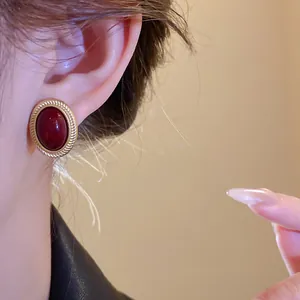 Close-up of elegant vintage oval red gemstone earring with a textured gold border