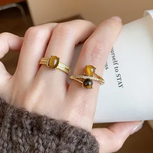 Detail of 18k gold plated rings with tiger's eye and zircon stones on a hand