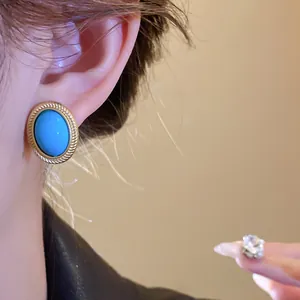 Detailed close-up showing a vintage oval blue gem earring with a gold-tone rope border.