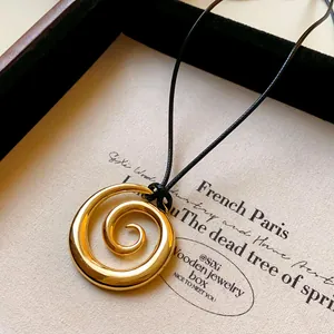 Dettaglio di una collana con ciondolo a spirale dorata minimalista in un portagioie premium