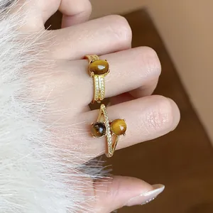 Close-up of vintage 18k gold plated tiger eye stone rings with zircon accents on hand.