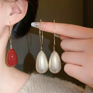 Detailed view of elegant teardrop pearl drop earrings in glossy red and white finishes.