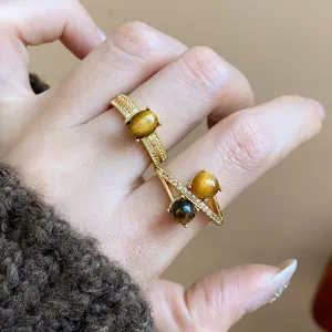 Detailed view of two 18k gold-plated tiger's eye rings with sparkling zircon accents