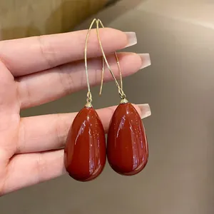 Close-up view of elegant red teardrop dangle earrings being held by hand to show detail