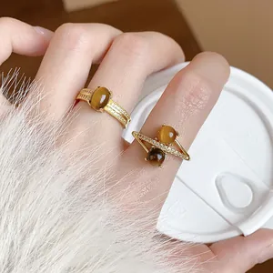 Detail view of 18k gold plated rings with tiger eye stones and zircons worn on finger