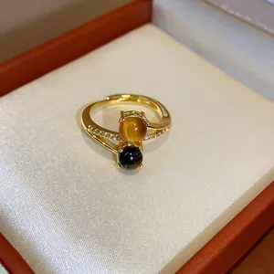 Close-up of 18k gold plated ring featuring tiger eye and dark spherical gemstones