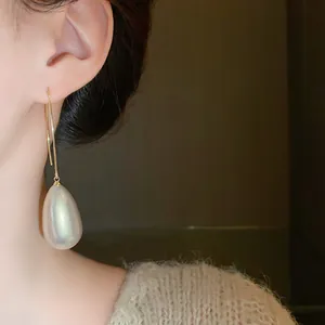 Detail view showing a vintage French gold teardrop pearl earring on model for jewelry shop