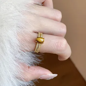 Close-up of elegant 18k gold tiger eye ring with zircon on white fur background