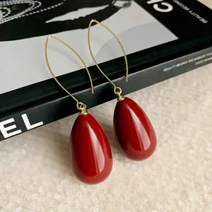 Close-up of elegant vintage-style red teardrop earrings with minimalist gold hooks