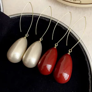 Close-up of elegant teardrop earrings in champagne and deep red on a velvet tray