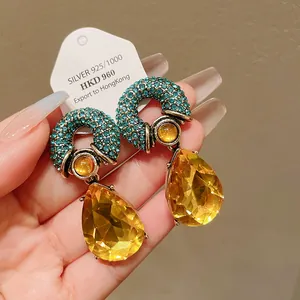 Close-up of vintage teardrop earrings with blue crystals and faceted amber glass drops.