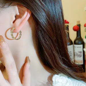 Detailaufnahme von eleganten Creolen mit 14k Vergoldung und Zirkonbesatz am Ohr