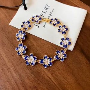 Bracciale a fiori in smalto blu Klein vintage con strass su sfondo di legno caldo