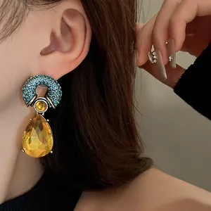 Close-up of vintage geometric earrings with blue rhinestones and yellow crystal drop