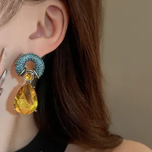 Detail view of retro teardrop earrings with blue crystals and yellow stone