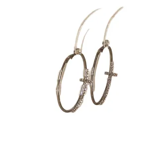 Silver needle hoop earrings with pavé diamond cross detail on white background