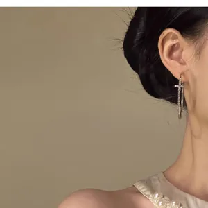 Detailed view of silver hoop earrings featuring a diamond-set cross charm pendant