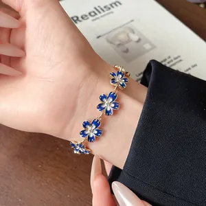 Dettaglio di un braccialetto di fiori in smalto blu Klein vintage con strass al polso.