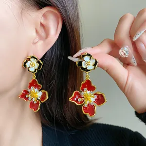 Close-up of elegant French vintage flower earrings with red enamel and rhinestones