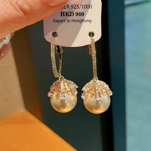 Detail view of elegant silver pearl earrings with geometric rhinestone flower design