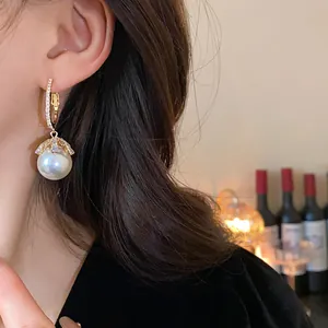 Elegant close-up view of pearl drop earring with diamond flower inlay worn by model