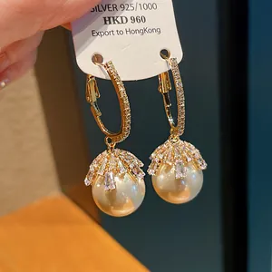 Close-up detail of luxury pearl earrings with crystal clusters on golden hoop frame