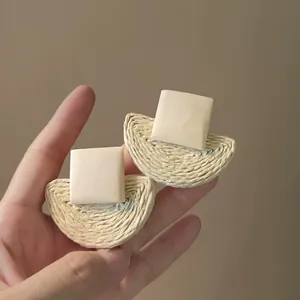 Detailed view of woven rattan geometric earrings with beige square studs