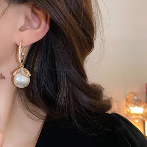 Elegant gold hoop earrings with pearl pendant and rhinestone flowers on model view