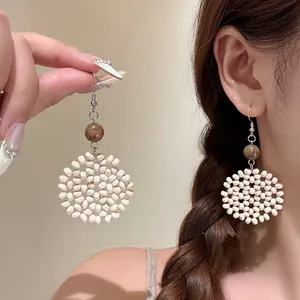 Detailed view of bohemian woven white bead flower drop earrings perfect for vacation styles
