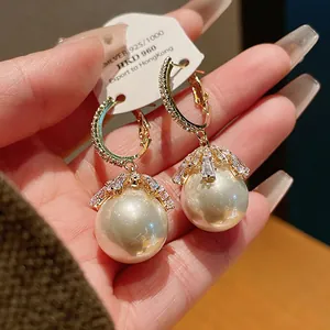 Close-up of elegant 925 silver needle pearl earrings with sparkling rhinestone floral caps.