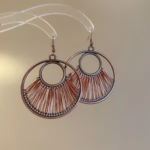 Macro detail of bohemian circular woven hoop earrings featuring bronze metallic finish