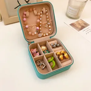 Primer plano de un joyero abierto de cuero verde menta con ranuras para anillos