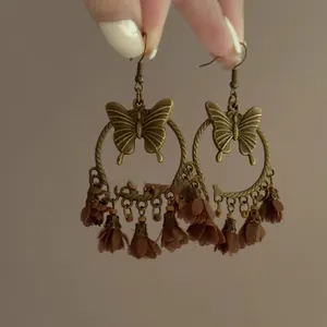 Detailed view of vintage bronze butterfly hoop earrings with brown fabric flower tassels