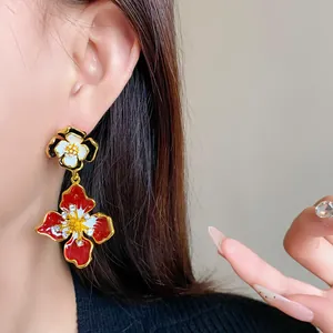 Macro view of French vintage floral drop earrings with red enamel and rhinestones