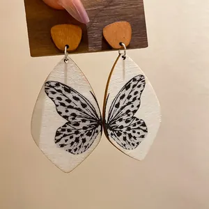 Close-up of bohemian butterfly wing print wooden teardrop earrings shown on a card