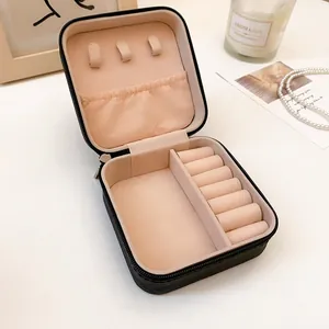 Detalle del joyero portátil de cuero negro que muestra compartimentos interiores rosas.