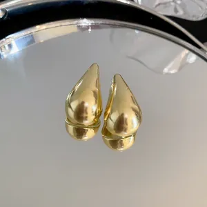 Vista detallada de pendientes geométricos de gota con acabado dorado y superficie pulida