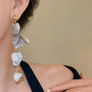 Primo piano dettagliato di orecchini pendenti con conchiglie geometriche irregolari indossati
