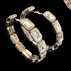 Close-up of sparkling rectangular crystal facets on oversized silver hoop earrings