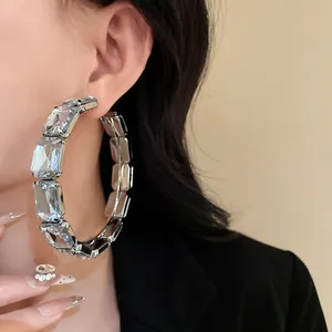 Close-up detail of oversized hoop earrings with shimmering rectangular crystals