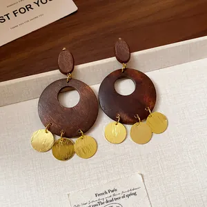 Close-up detail of vintage geometric wooden drop earrings with polished gold charms