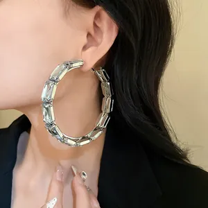 Close-up of oversized silver-tone hoop earring with rectangular crystals