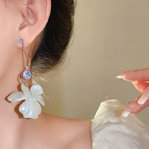 Elegante Silberohrringe mit Zirkon und weißen Blütenblättern am Modell