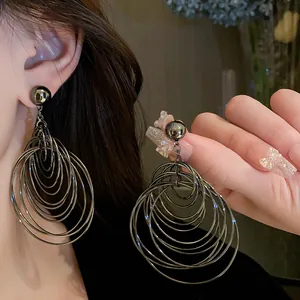 Close-up of gunmetal multi-layered hoop earrings on an ear, showing metallic texture.