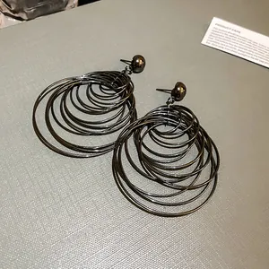 Close-up of multi-layered metallic hoop earrings with creative circular design