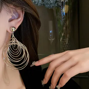 Close-up detail showing multi-layer silver concentric circle hoop earrings worn on an ear