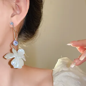 Nahaufnahme eleganter Ohrringe mit Zirkonia und weißer Perlmuttblume am Model getragen