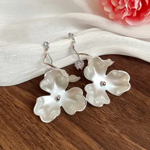 Detailansicht eleganter weißer Blumenohrringe mit funkelnden Zirkon-Akzenten